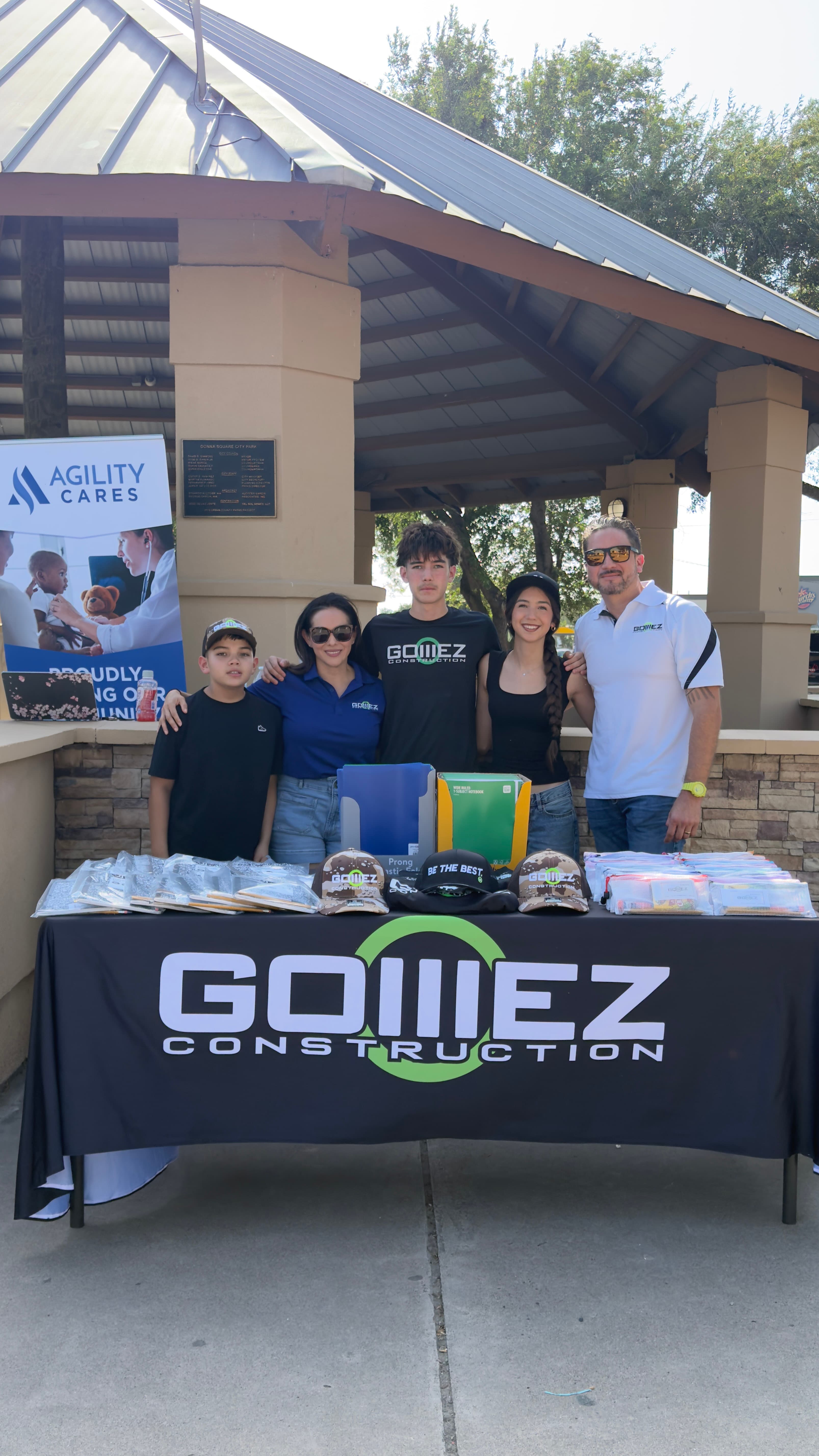 Efrain Gomez Jr. with his family behind a table of school supplies and backpacks at an outdoor community giveaway